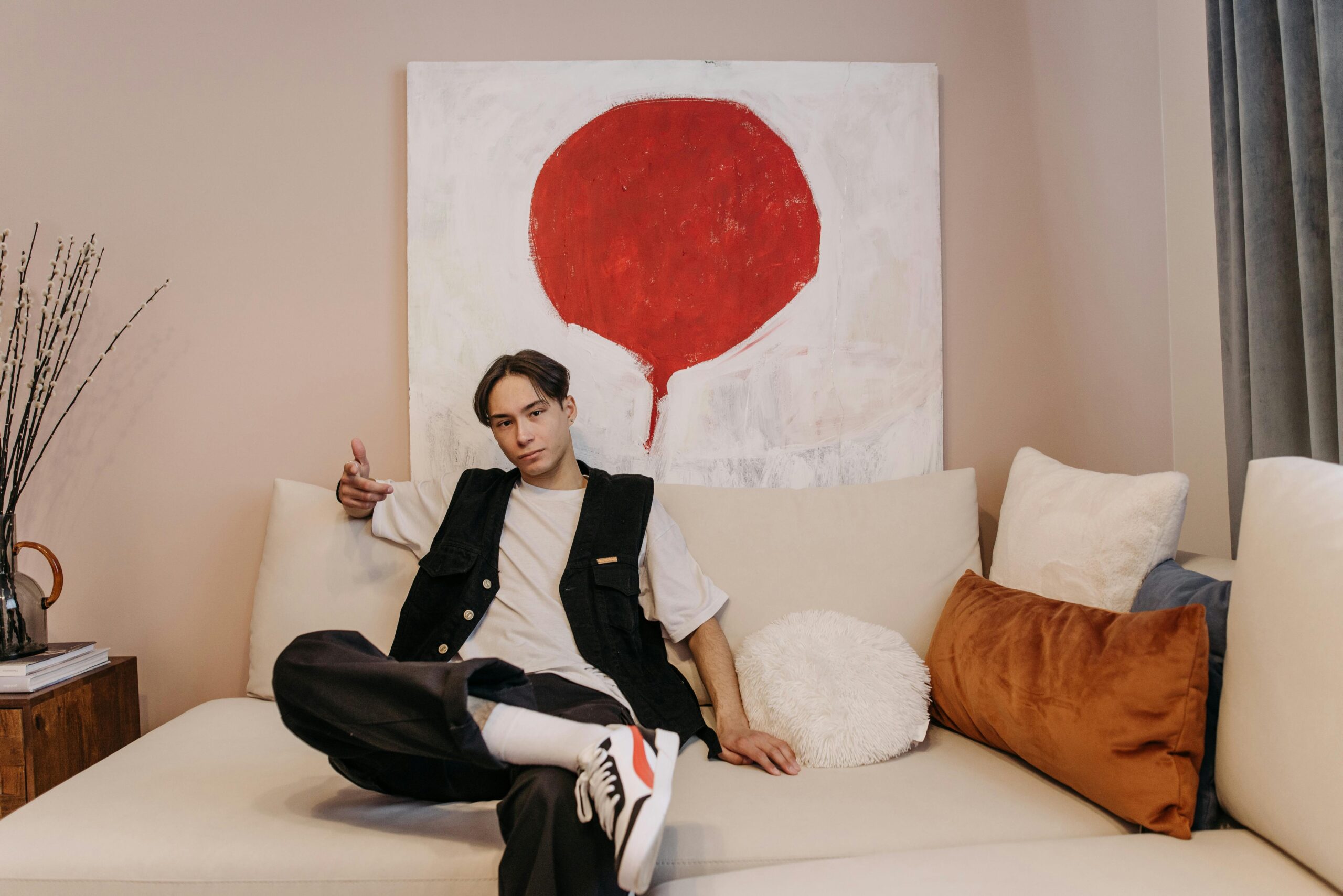 Young man relaxing on a modern couch with abstract painting in background.